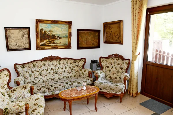 Salon w Domu Gościnnym Michał w Pobierowie — rzeźbione meble w kwiatowej tapicerce, stolik z marmurowym blatem i obrazy.